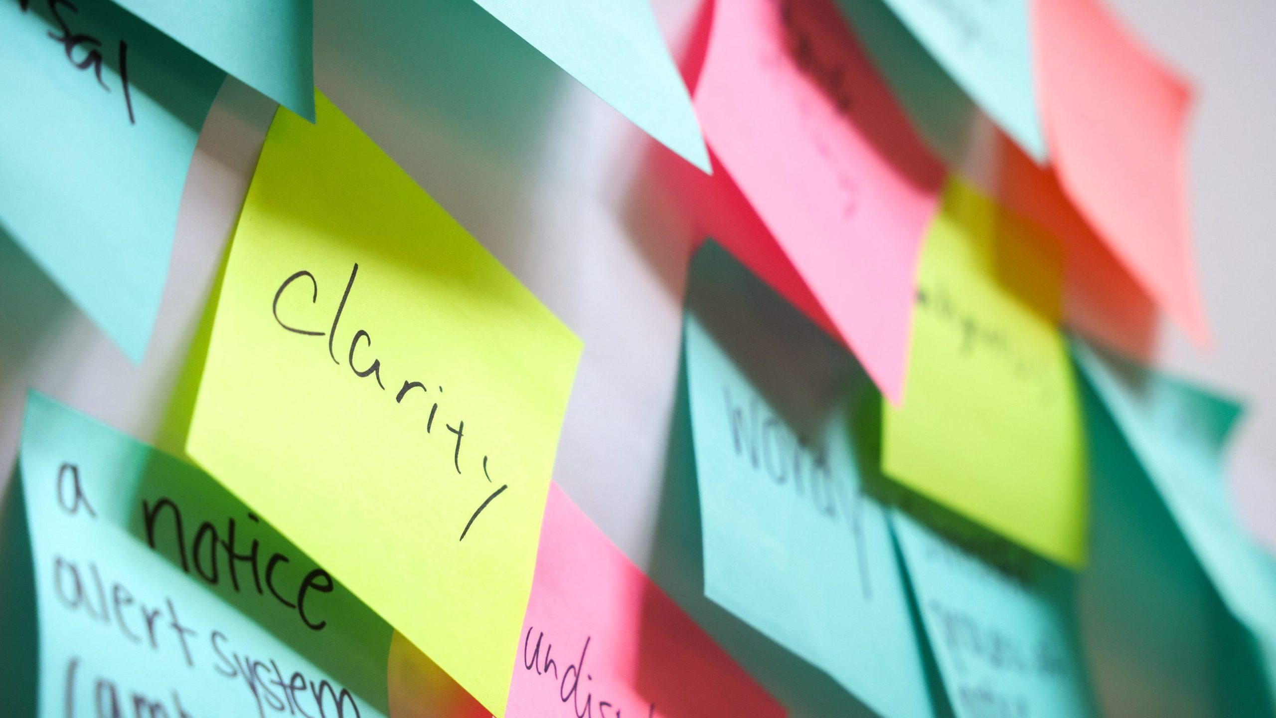 Post it notes of various colors with writing on them in black marker. Word "clarity" is visible on one. 